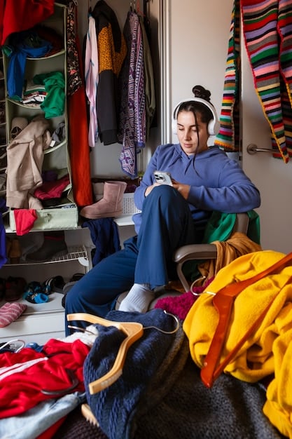 A person sorting through a pile of colorful clothing, deciding which items to keep or donate, with a focus on decluttering and simplifying a wardrobe.