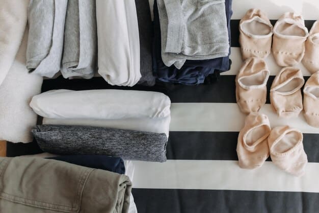 A neatly organized capsule wardrobe featuring neutral-colored clothing items such as a white button-down shirt, black trousers, a denim jacket, and a beige sweater. The wardrobe also includes a pair of ankle boots and a simple tote bag.