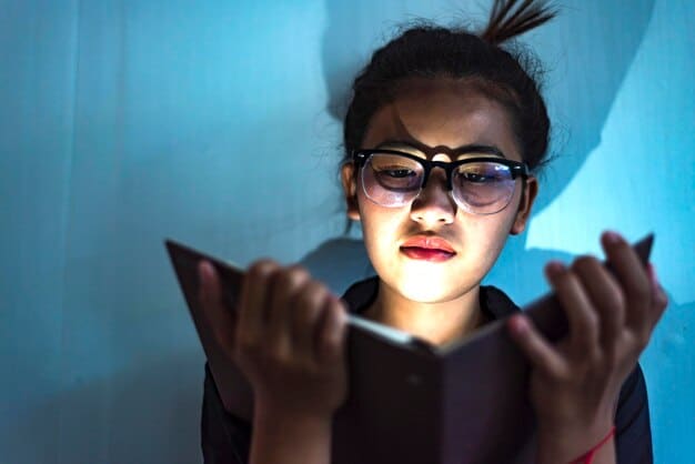 A close-up of a person's eyes looking at a brightly lit smartphone screen in a dark room, with the harsh blue light reflecting in their pupils.