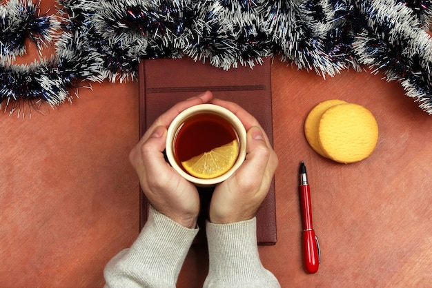 A close-up shot of a person's hands holding a warm cup of tea in the morning light. The background is blurred, showing a peaceful, minimalist kitchen with natural elements like plants and wooden surfaces.