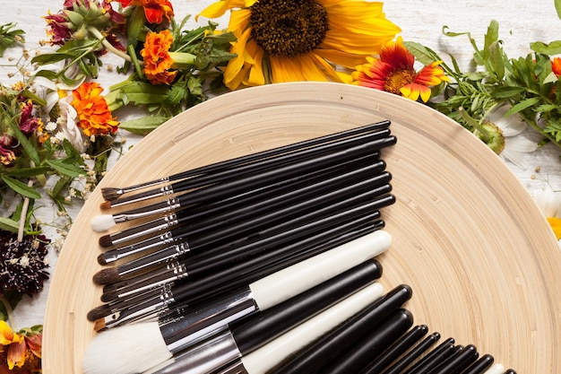 A variety of eyeliner brushes laid out on a makeup table, including angled, fine-tip, and flat brushes, each with a small amount of product on the tip to demonstrate their use.