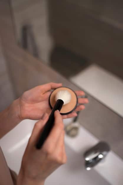 Close-up of a woman's hand gently exfoliating her face with a soft brush, showcasing the importance of skin preparation for optimal makeup application.