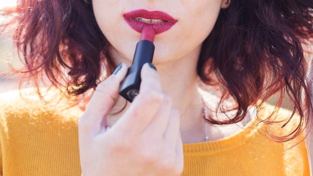 A hand applying dark pink lipstick to the center of the lips with a lip brush. Focus is on the precise application and the texture of the lipstick.