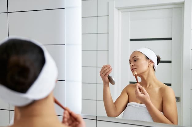 A close-up shot of a woman's hands applying a small amount of cleanser to her face in front of a bathroom mirror. The focus is on gentle application and quick movement.