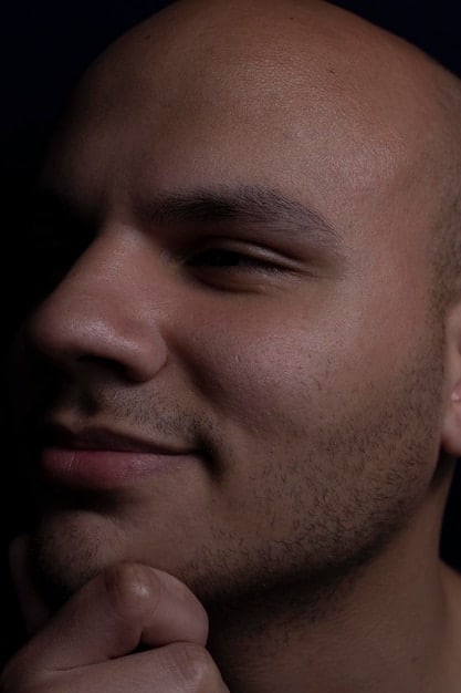 A close-up shot of a man's face, showing the texture of his skin. Visible are enlarged pores, some acne scars, and a few wrinkles around the eyes. The lighting is soft and natural, highlighting the skin's imperfections.