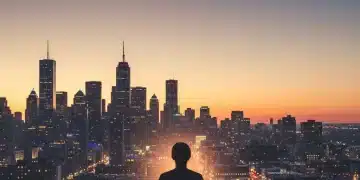 Person meditating on a rooftop overlooking a city at dusk, practicing mindfulness.